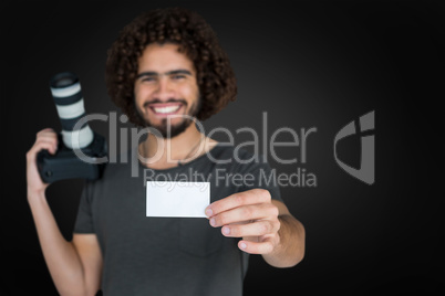 Composite image of portrait of smiling male photographer showing card while holding camera