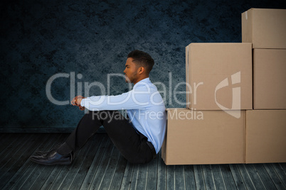 Composite image of businessman leaning on cardboard boxes against white background