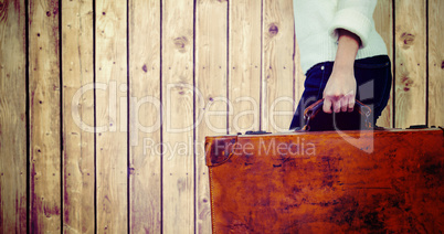 Composite image of low section of woman carrying vintage suitcase