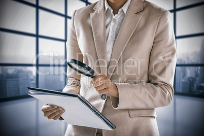 Composite image of businesswoman looking at document through magnifying glass