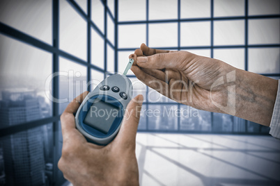 Composite image of close up of man hand testing blood sugar with glucometer