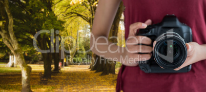 Composite image of mid section of woman holding digital camera