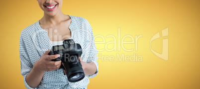 Composite image of portrait of smiling young woman holding digital camera