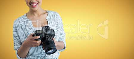 Composite image of portrait of smiling young woman holding digital camera