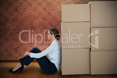 Composite image of businesswoman leaning on cardboard boxes against white background