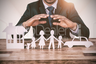 Composite image of underwriter protecting family in paper with his hands