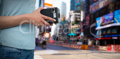 Composite image of mid section of photographer holding vintage camera