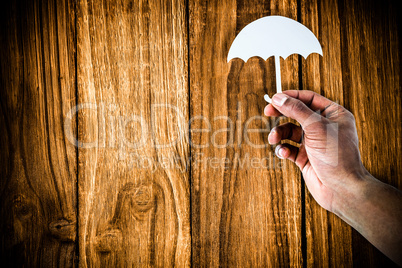 Composite image of hand holding an umbrella in paper