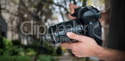 Composite image of mid section of male photographer holding camera