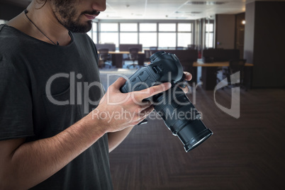 Composite image of young photographer operating digital camera