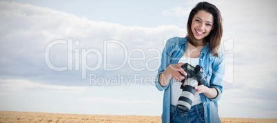 Composite image of portrait of young female photographer holding digital camera