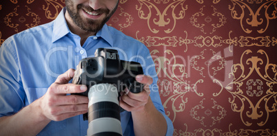 Composite image of smiling young male photographer looking at digital camera