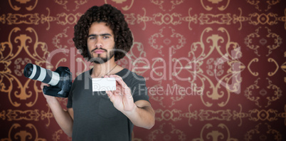 Composite image of portrait of male photographer showing card while holding camera