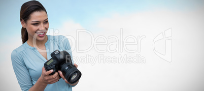 Composite image of thoughtful smiling female photographer holding digital camera