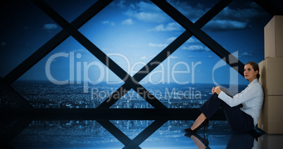 Composite image of businesswoman leaning on cardboard boxes against white background