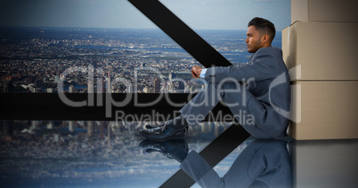 Composite image of businessman leaning on cardboard boxes against white background