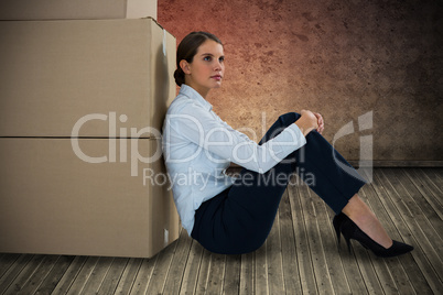 Composite image of businesswoman leaning on cardboard boxes against white background