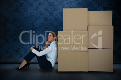 Composite image of businesswoman leaning on cardboard boxes against white background