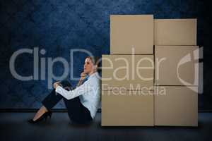 Composite image of businesswoman leaning on cardboard boxes against white background