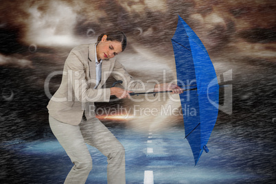Composite image of full length of businesswoman struggling with blue umbrella