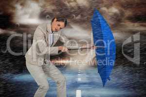 Composite image of full length of businesswoman struggling with blue umbrella