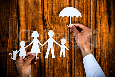Composite image of hand holding an umbrella and a family in paper