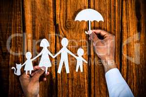 Composite image of hand holding an umbrella and a family in paper