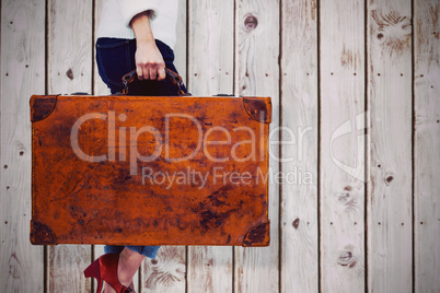 Composite image of low section of woman holding vintage suitcase