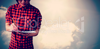 Composite image of mid section of young man writing on notebook