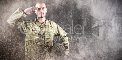 Composite image of portrait of confident soldier holding helmet while saluting