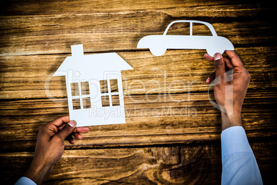 Composite image of man holding a car and a house in paper