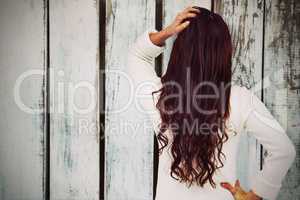 Composite image of full length rear view of brunette with hand in hair
