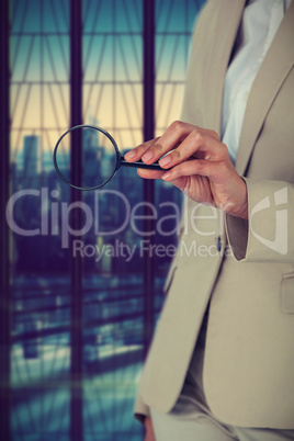 Composite image of midsection of businesswoman holding magnifying glass