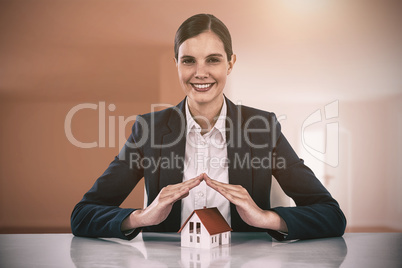 Composite image of insurer protecting a house by his hands