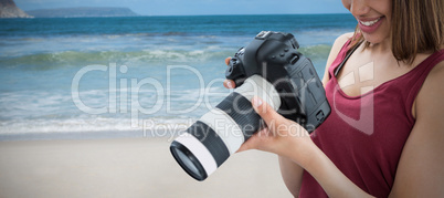 Composite image of happy young female photographer looking at digital camera