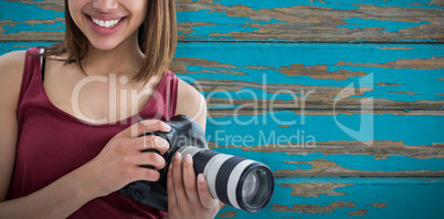 Composite image of portrait of smiling beautiful woman holding digital camera