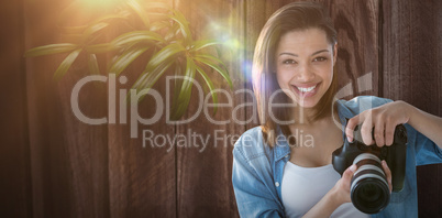 Composite image of portrait of smiling female photographer holding digital camera