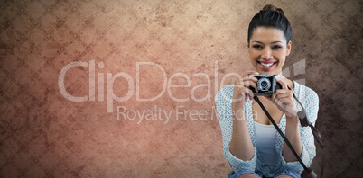 Composite image of portrait of happy young woman holding camera