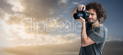 Composite image of young man photographing with digital camera