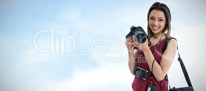 Composite image of portrait of happy young woman holding digital camera