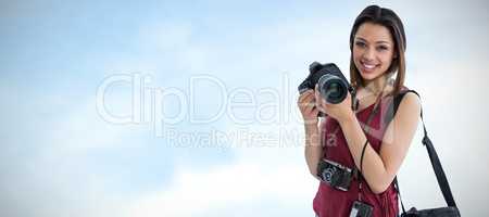 Composite image of portrait of happy young woman holding digital camera