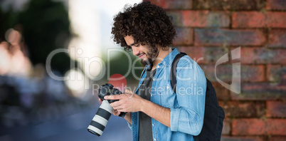 Composite image of young male photographer operating camera