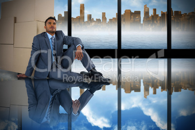 Composite image of businessman leaning on cardboard boxes against white background