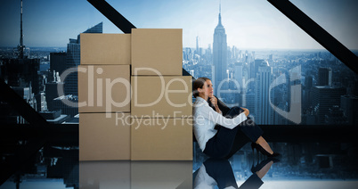 Composite image of businesswoman leaning on cardboard boxes against white background