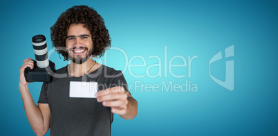 Composite image of portrait of smiling photographer showing card while holding camera