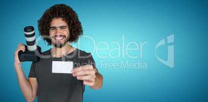 Composite image of portrait of smiling photographer showing card while holding camera