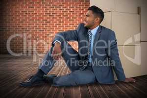 Composite image of businessman sitting near cardboard boxes against white background