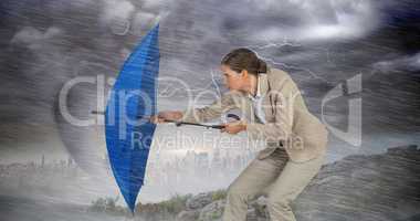 Composite image of full length of businesswoman defending with blue umbrella