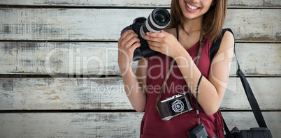 Composite image of portrait of smiling young woman holding digital camera