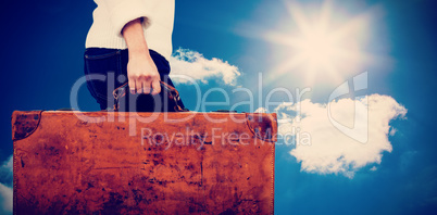 Composite image of low section of woman holding vintage suitcase